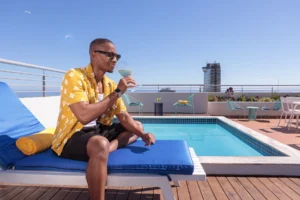 Guest relaxing with a cocktail by the rooftop pool at Home Suite Hotels Sea Point